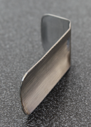 Small slipper shim made from stainless steel and curved using a folding machine to fit the pole diameter